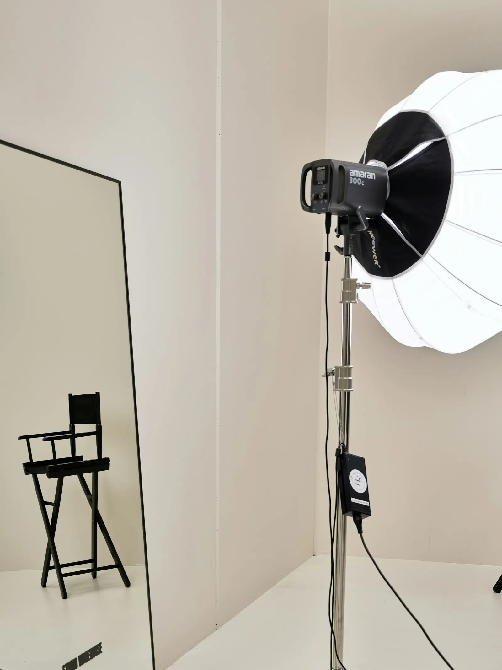 A bright white photo studio with a softbox light and a director's chair
