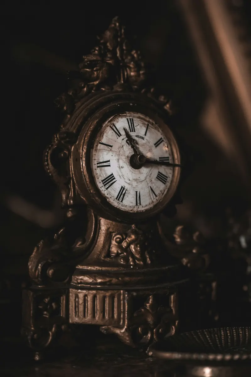 An ornate antique mantel clock with a white dial