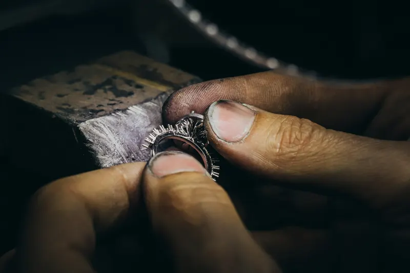 Fingers holding a ring at a jeweller's bench