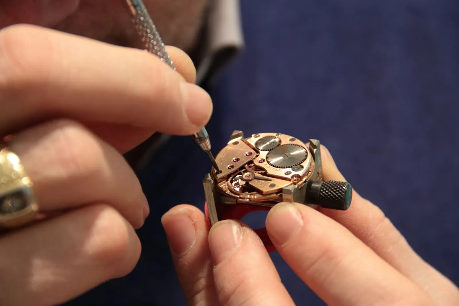 Hands working on a small watch movement with a fine tool